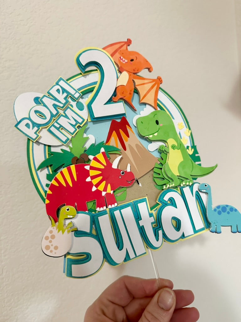 Custom dinosaur "Roar Im 2" cake topper with red green and orange dinosaurs